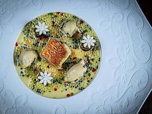 Gourmetgericht mit gebratenem Fisch, Nocken und Perlengemüse in cremiger Sauce