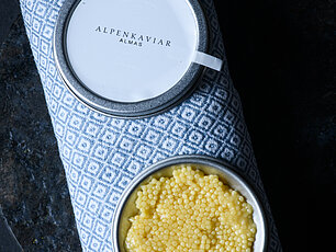 Offene Dose Almas Alpenkaviar mit gelbem Kaviar auf gemustertem Tuch